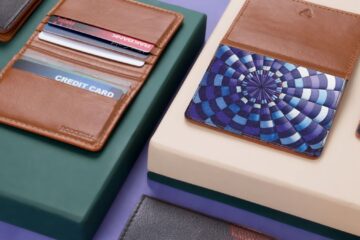 Close-up of assorted leather wallets and cardholders on a modern violet and green background.