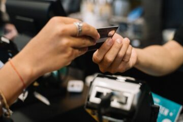 Close-up of hands completing a payment transaction at a retail checkout using a bank card.