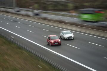 Two cars moving fast on a highway, showcasing speed and travel in motion.
