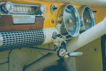 Close-up of a classic vintage car dashboard featuring an analog radio, speedometer, and keys.