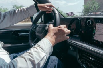A person driving a modern car while using the built-in GPS navigation system.